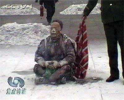 Waiting for a cue: In a poorly acted scene, a policeman stands waiting beside a supposed self-immolating Falun Gong practitioner.  This is just one of dozens of suspicious points in this horrific scam.